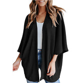 Woman in black waffle knit kimono cardigan and jeans.