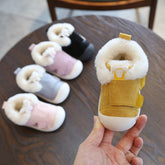 Five colorful fur-lined baby shoes, one held in hand.