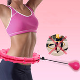 A woman in a pink sports bra uses a pink smart hula hoop.