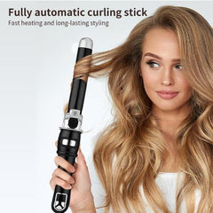 A woman holding a fully automatic black curling stick to her long, curling blonde hair.