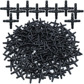 A large pile of black plastic four-way drip irrigation connectors.