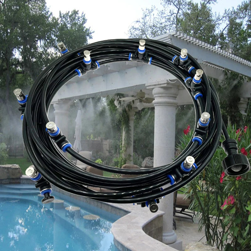 A coil of black misting hose with silver nozzles over a pool patio.