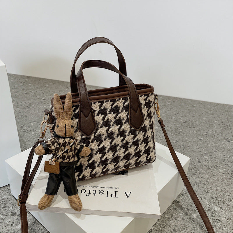 Houndstooth handbag with brown trim and a bunny keychain.