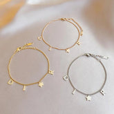 Three charm bracelets spelling "DIOR" in gold, rose, and silver.