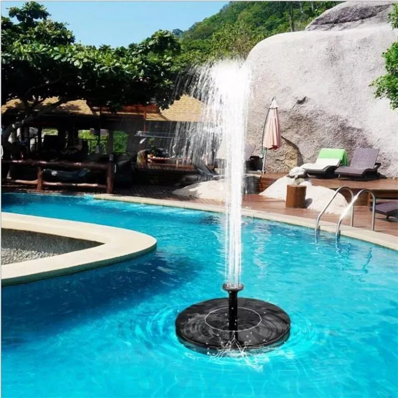 A round black solar water fountain floating in blue water with a jet of water spraying up.