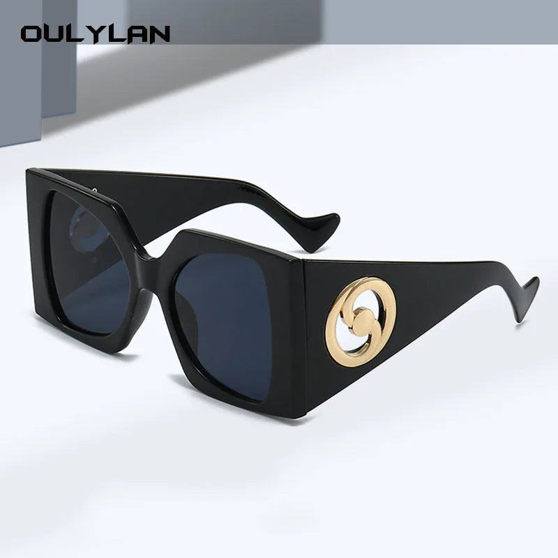 Black angular oversized sunglasses with gold side logo.