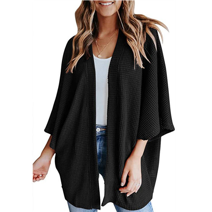 Woman in black waffle knit kimono cardigan and jeans.