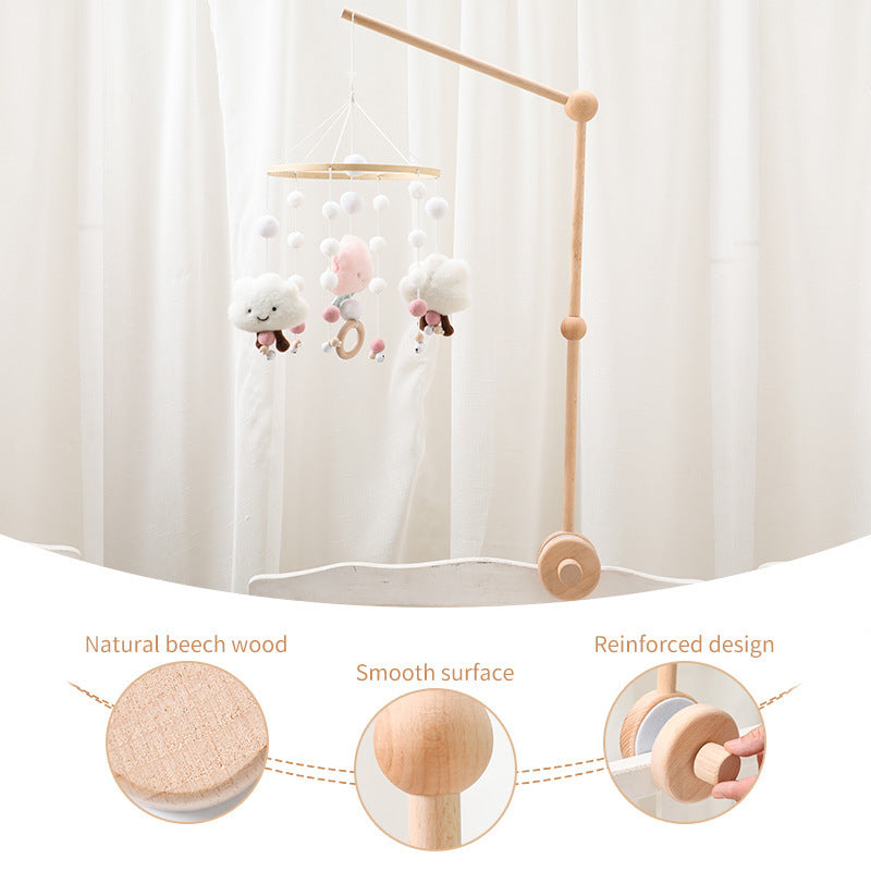 Wooden baby mobile with cloud and pom-pom hangings, showing wood details.
