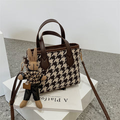 Houndstooth handbag with brown trim and a bunny keychain.