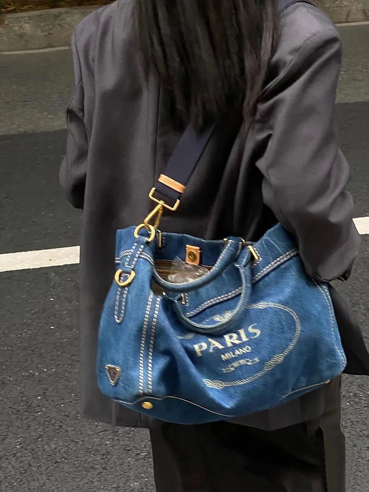 Person carrying a denim tote bag with "PARIS" text.