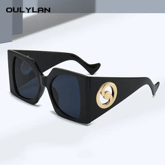Black angular oversized sunglasses with gold side logo.