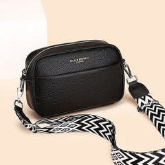 Black pebbled crossbody bag with wide chevron strap.